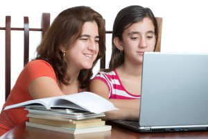 Hispanic teen and her mother working or browsing the web on a laptop computer isolated on white