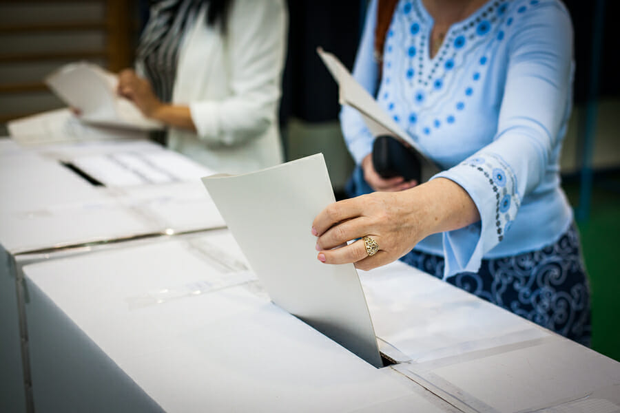 Hand of a person casting a ballot at a polling station during voting.